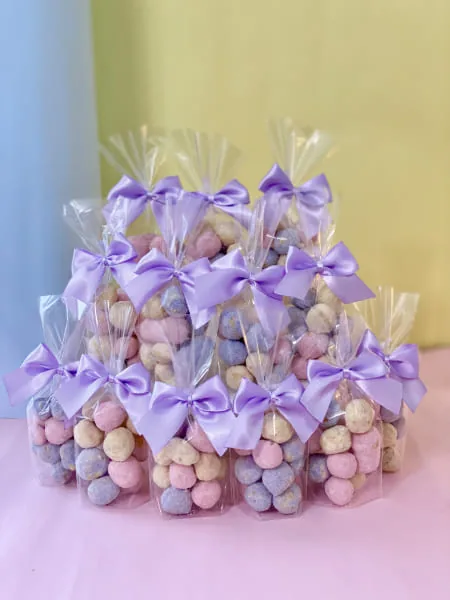 Pipocas gourmet coloridas em embalagens com laço lilás